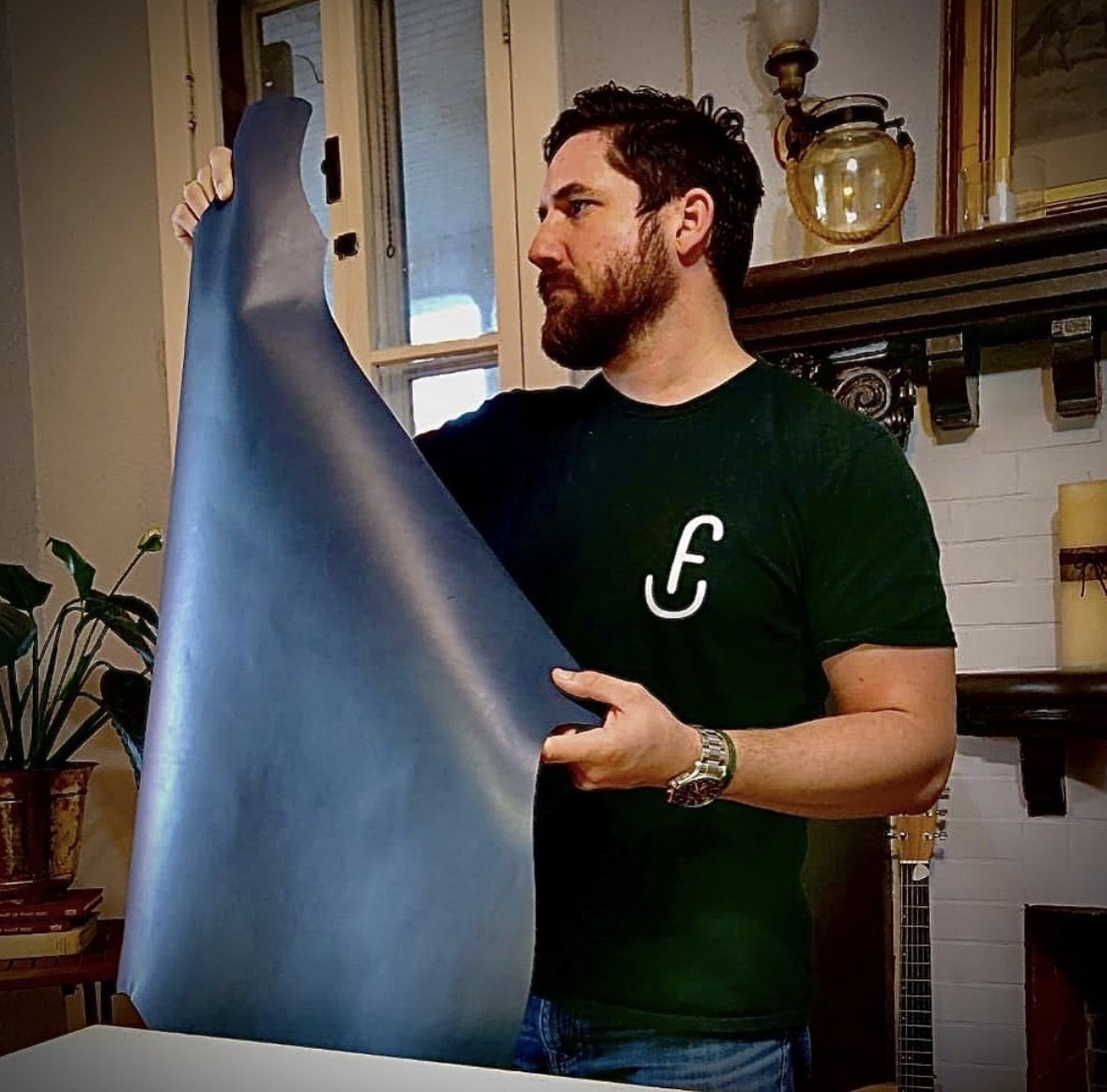 Francisco Flores holding a full hide in his atelier